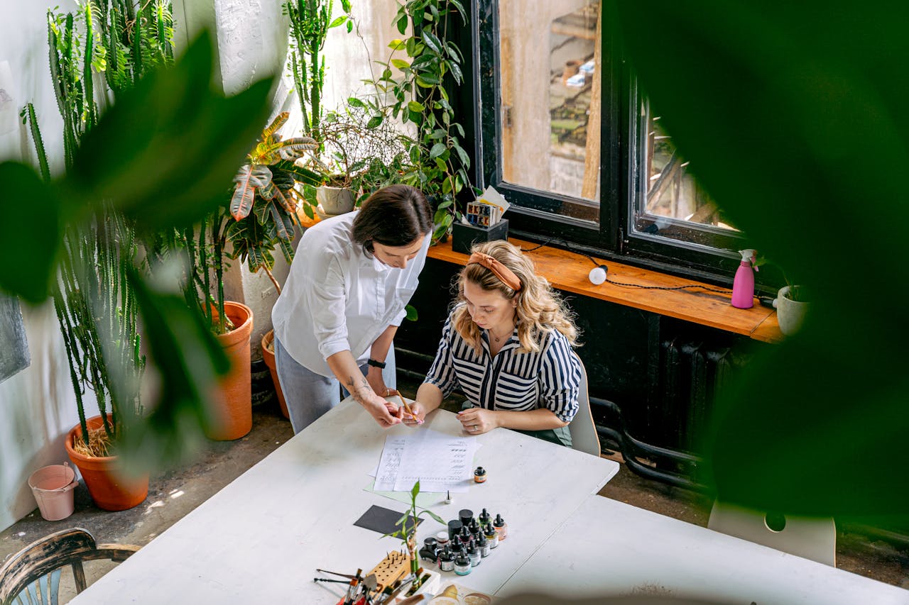 Two women collaborating on a project in an art-filled studio space.