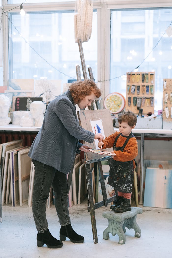 Adult assisting child with painting in a creative art studio setting.