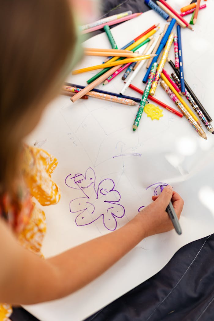 A child creatively drawing with colored pencils at home, showcasing artistic imagination.